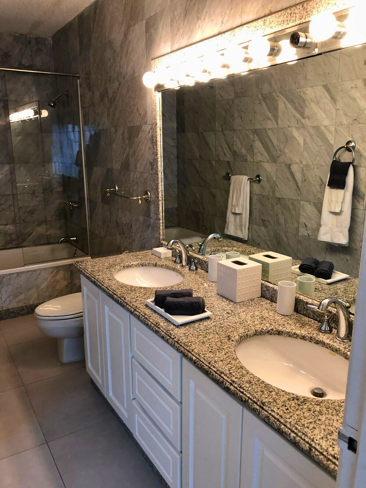 A bathroom with two sinks, a glass shower enclosure, and a vanity with a mirror.