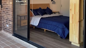 A bedroom with a large sliding glass door, a wooden headboard, and a bed with blue bedding. - Charming 1-bedroom apartment in marvelous Bogotá with WiFi (Bogotá)