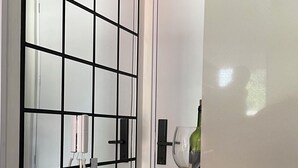 A modern kitchen with a black and white color scheme, featuring a glass partition, a wine glass, and a telephone on the wall. - Charming 1-bedroom apartment in marvelous Bogotá with WiFi (Bogotá)