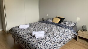 A neatly made bed with a patterned bedspread, two pillows, and two rolled towels. - Maison Ty'Bell-At the gateway to the Gulf of Morbihan  (Moustoir-Ac)