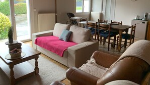 A cozy living room with a sofa, a coffee table, and a dining area with a table and chairs. - Maison Ty'Bell-At the gateway to the Gulf of Morbihan  (Moustoir-Ac)