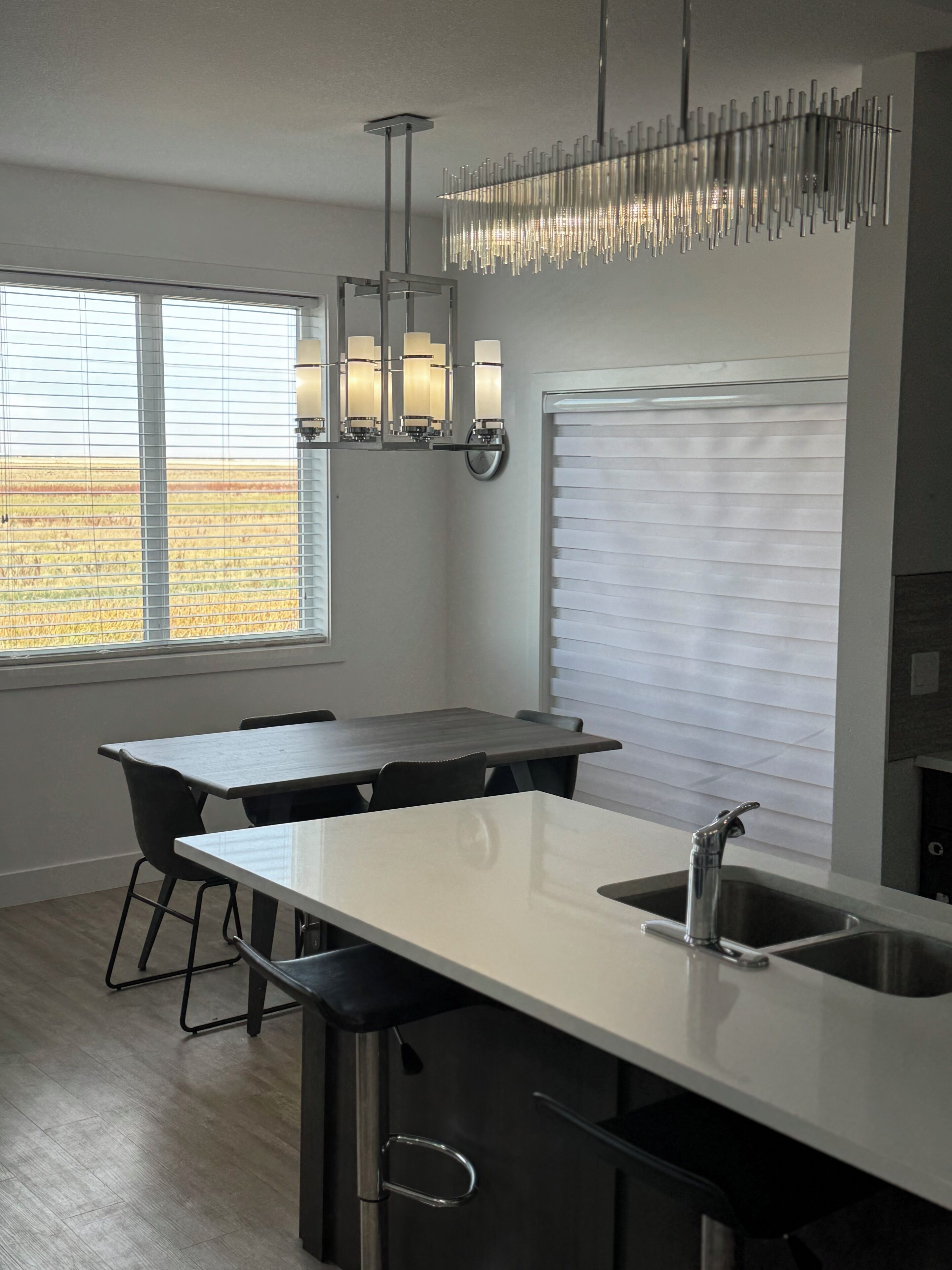 A modern kitchen with a central island, stainless steel sink, and pendant lighting.