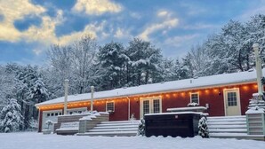 A red building with a snow-covered roof, surrounded by trees.