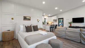 A modern bedroom with a large bed, a sofa, and a desk area.
