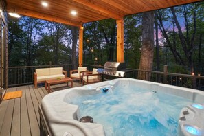 Une terrasse en bois avec un jacuzzi, du mobilier d’extérieur et un barbecue.