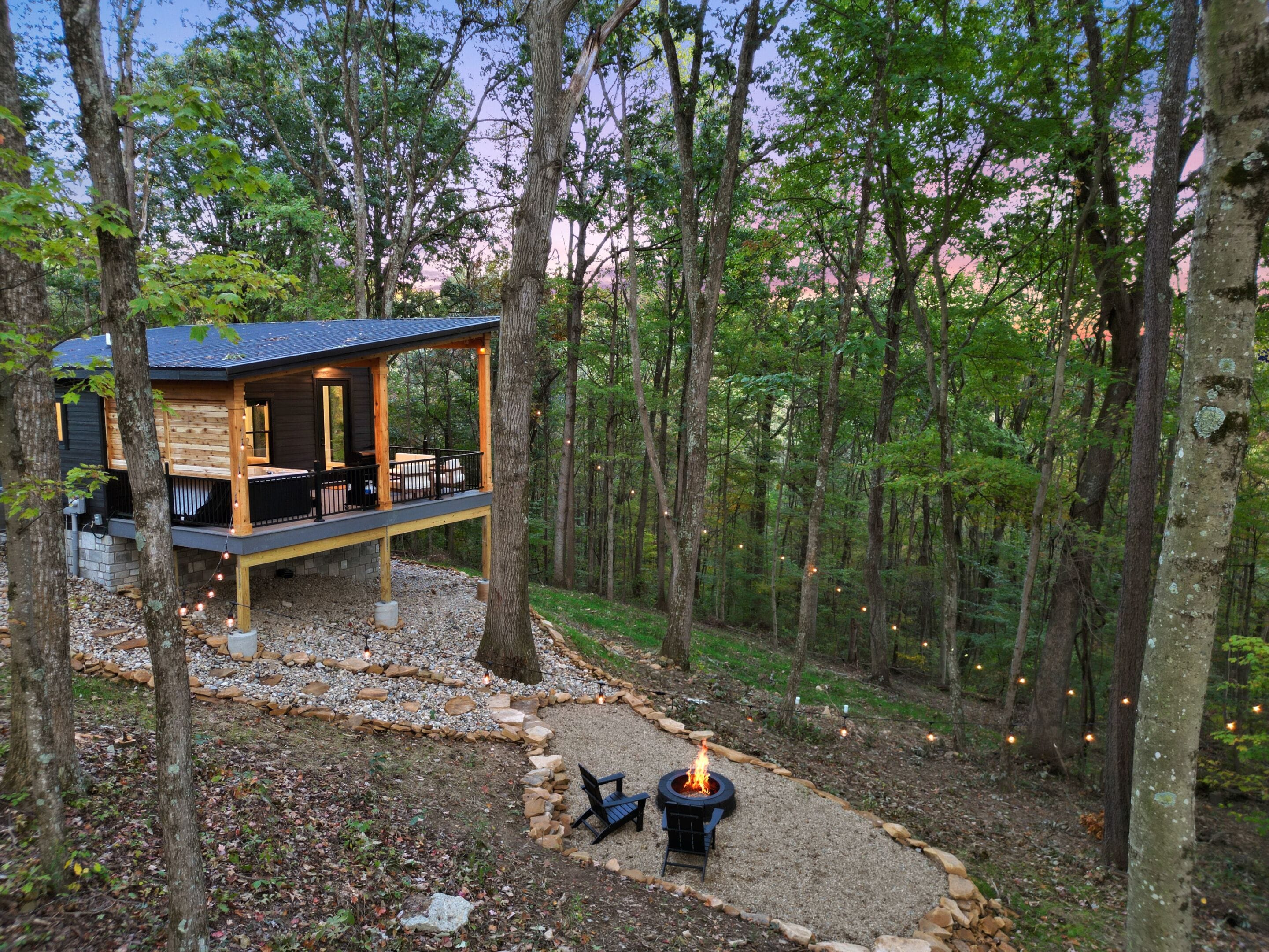 A cabin with a deck, a fire pit, and a stone pathway.