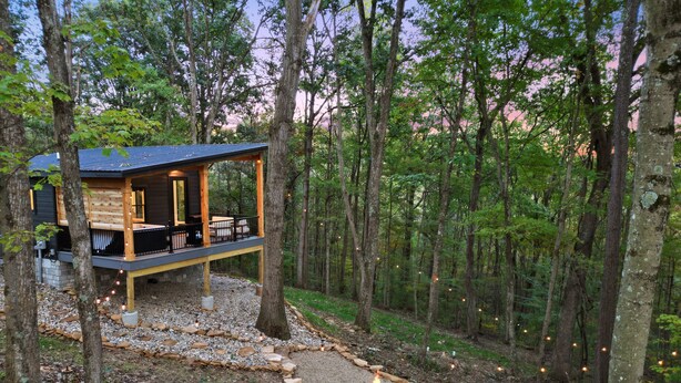 A cabin with a deck, a fire pit, and a stone pathway.