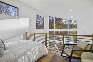 Une chambre à coucher avec un lit, une chaise et un balcon donnant sur des arbres.