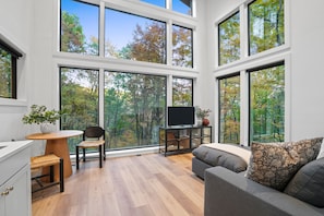 Enjoy expansive forest views from the large windows in this cozy living space with a comfortable seating area and flat-screen TV.