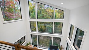 A multi-level interior with large windows offering views of a forest.