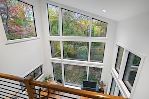 Interior de varios niveles con ventanas amplias que ofrecen vistas a un bosque.