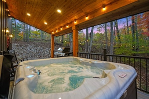 Un jacuzzi bajo una terraza de madera con vistas a un bosque.