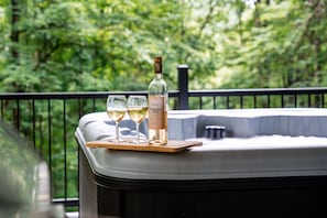Un bain à remous avec une bouteille de vin et deux verres sur un plateau en bois.