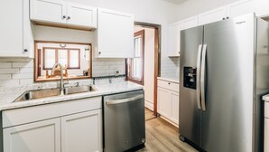 A modern kitchen with white cabinetry, stainless steel appliances, and a built-in dishwasher.