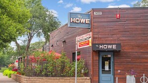 A building with a sign reading "The HOWE DAILY KITCHEN & BAR" and a smaller sign indicating "Happy Hour 11AM-5PM MONDAY-FRIDAY."