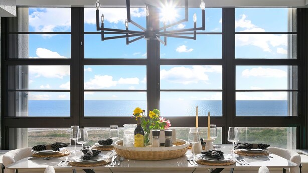 A dining table set with plates, glasses, and a centerpiece with flowers and salt and pepper shakers. - Stylish Front Corner Beachfront Resort | 5⭐️ Local Host | Balcony | Views (Marco Island)