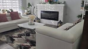 A modern living room with a white sofa, a fireplace, and a coffee table.