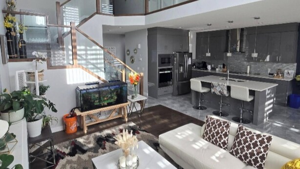 A spacious living area with a white sofa, a coffee table, and a staircase leading to an upper level.