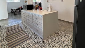 Une cuisine spacieuse dotée d’un îlot central, d’un coin repas avec des chaises et d’un réfrigérateur.