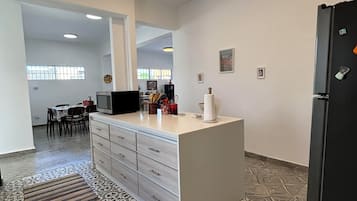 Una cocina amplia con una isla central, un comedor con sillas y un refrigerador.