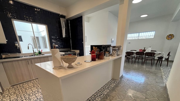Une cuisine moderne dotée d’un îlot central, d’un coin repas avec une table et des chaises, et de carreaux de sol à motifs.
