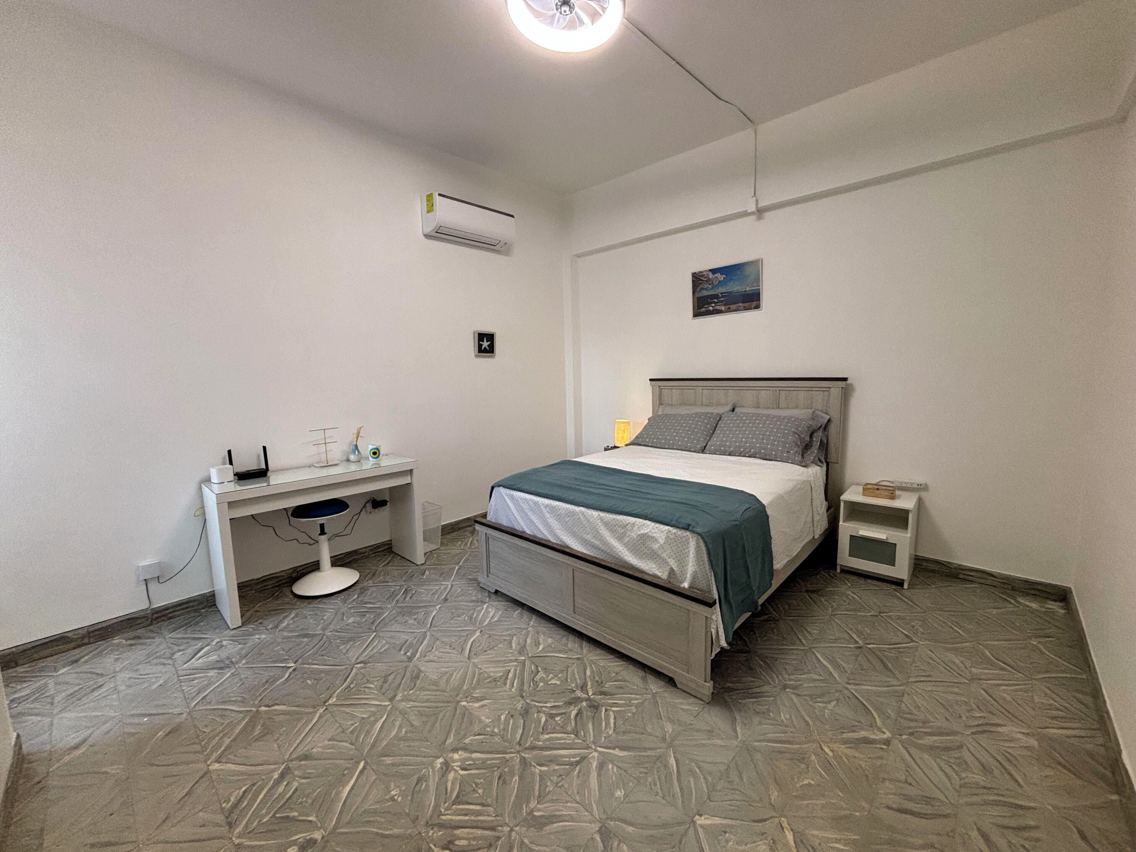 Un dormitorio con cama, escritorio y aire acondicionado.