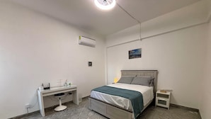 Une chambre à coucher avec un lit, un bureau et un climatiseur.