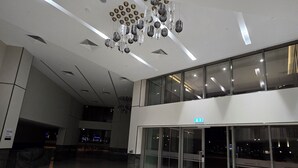 Eine geräumige Lobby mit modernem Deckenbau, großen Fenstern und einer Glastür.