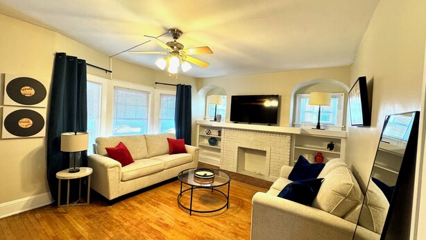 A living room with a beige sofa, a red and blue couch, a coffee table, a TV, and a fireplace.