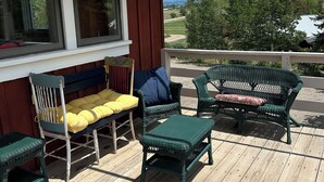 A wooden deck with outdoor furniture, including chairs and a bench, and a view of the landscape.