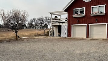 A red barn with two garage doors, a covered porch, and a gravel driveway.