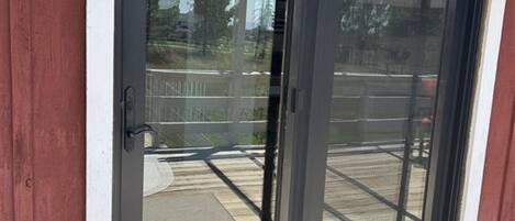 Una porta scorrevole in vetro con maniglia in metallo, che dà accesso a un patio coperto.