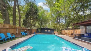 A backyard with a swimming pool, blue chairs, and a wooden deck.