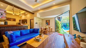 Un salon moderne avec un canapé bleu, une table basse en bois et un coin repas comprenant des chaises et une table.