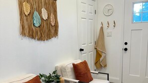 A room with two white armchairs, a small table with a plant, and a macrame wall hanging. - Cozy 2-beds Family Friendly Apt w/ Pool, Full Kitchen in Downtown Kissimmee (Kissimmee)
