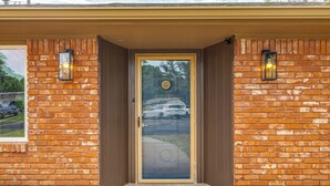 A brick house with a glass door and two wall-mounted lights.