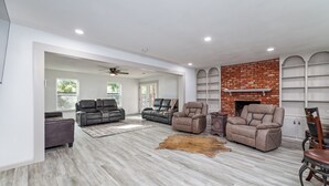 A spacious living room with a fireplace, leather sofas, and a wooden floor.