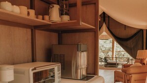A compact kitchen with a retro toaster, a coffee maker, and wooden shelves. - Lantana - Luxury Glamping Tent (Blanco County)