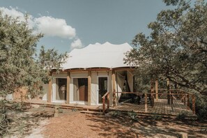 Eine rustikale Holzhütte mit einer Holzterrasse und einer Veranda, umgeben von Bäumen.