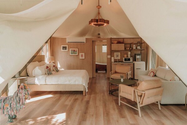 Ein gemütliches Schlafzimmer im Dachgeschoss mit Bett, Stuhl, kleinem Tisch und einer Küchenzeile.