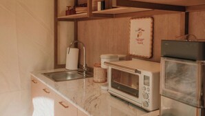 A compact kitchen with wooden shelves, a built-in microwave, and a stainless steel sink.