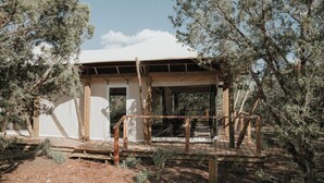 A wooden cabin with a covered porch, surrounded by trees.