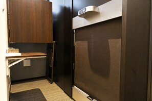 Una kitchenette compacta con refrigerador, microondas y una pequeña superficie de apoyo.