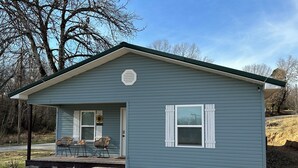 A small, single-story house with a porch, a covered entryway, and a small front yard. - corporate comfort suits  (Pocahontas)