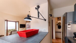 A modern kitchen with a black countertop, a red bowl, and a pendant light.