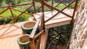 A staircase with a wooden handrail, metal steps, and a view of greenery below.