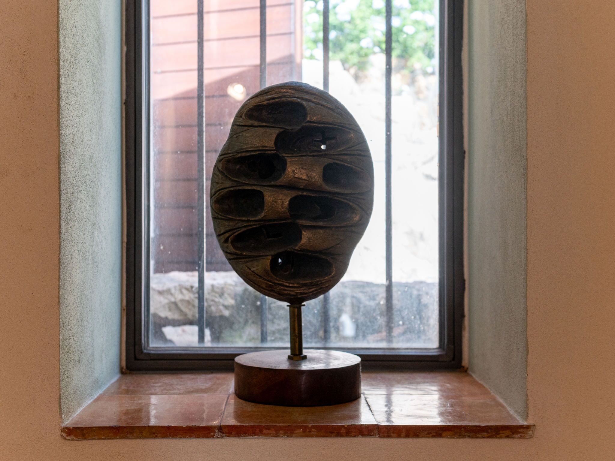 Una escultura con base circular sobre un alféizar.