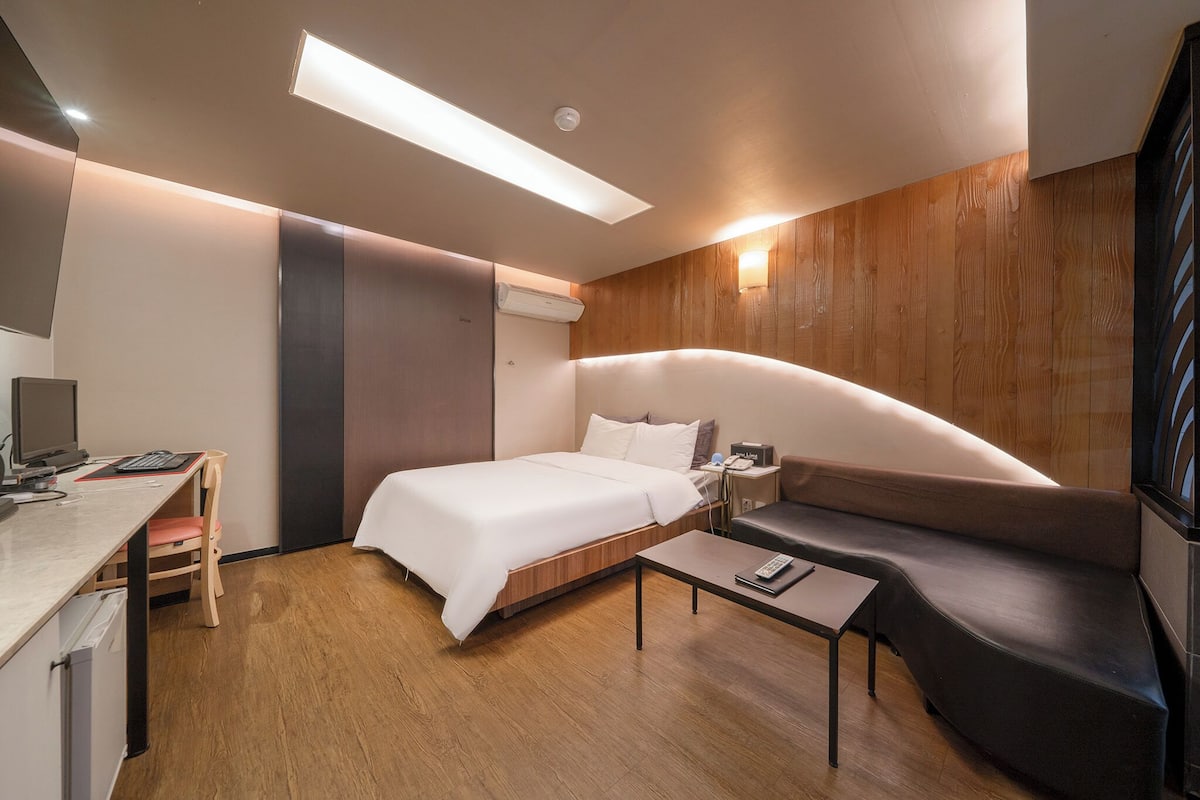 Une chambre d’hôtel moderne équipée d’un lit, d’un bureau, d’une chaise, d’un canapé et d’un téléviseur à écran plat.