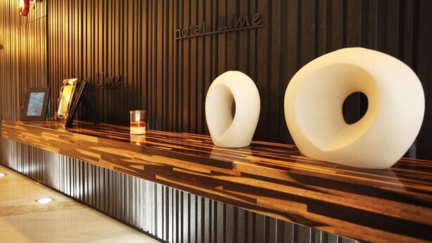 Ein moderner Hotelrezeptionstresen mit Holzoptik und einem Schild mit der Aufschrift 'hotel Lime'.