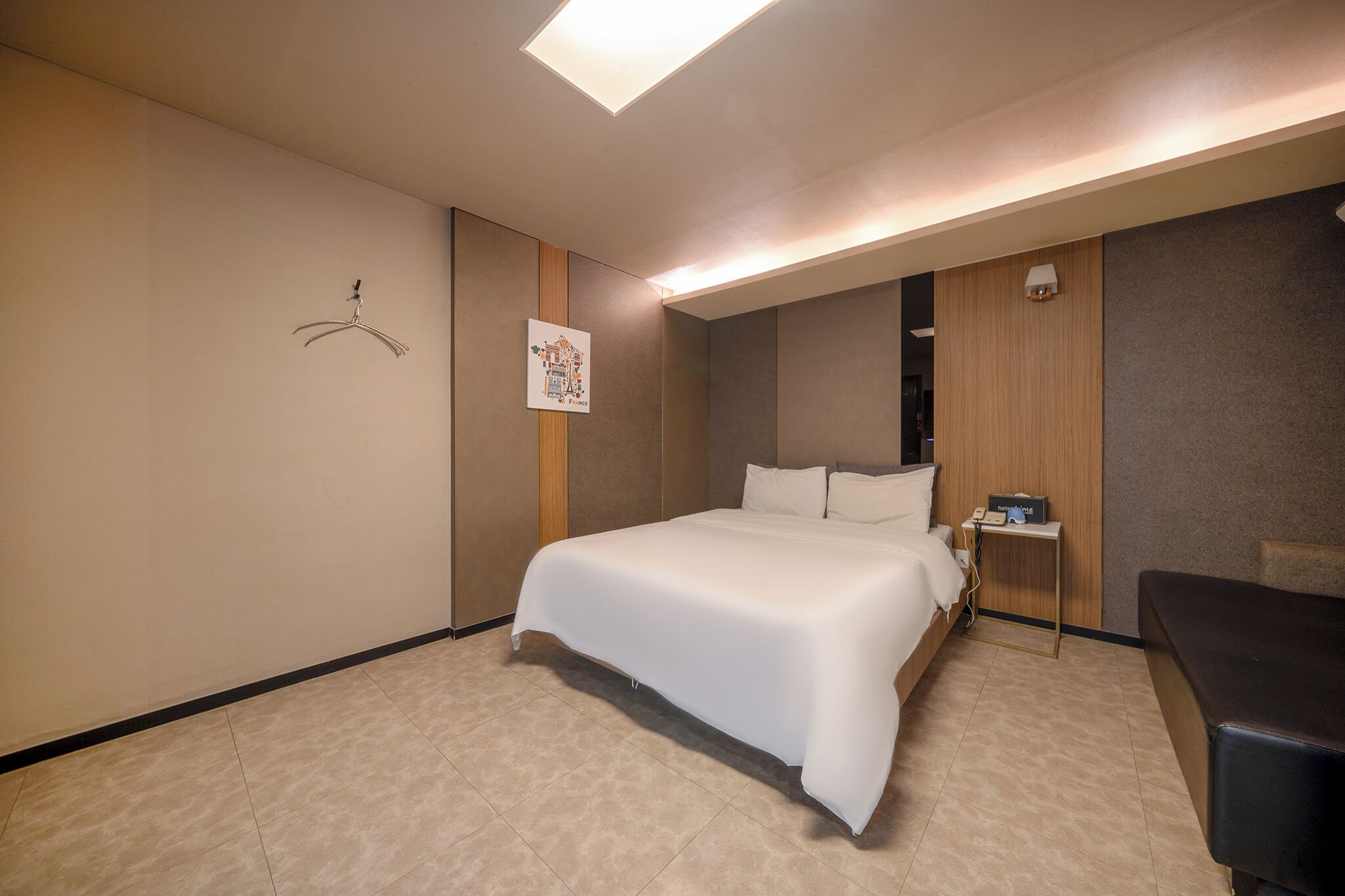 Una habitación de hotel con una cama grande, una mesita de noche con lámpara y un escritorio pequeño con computadora.